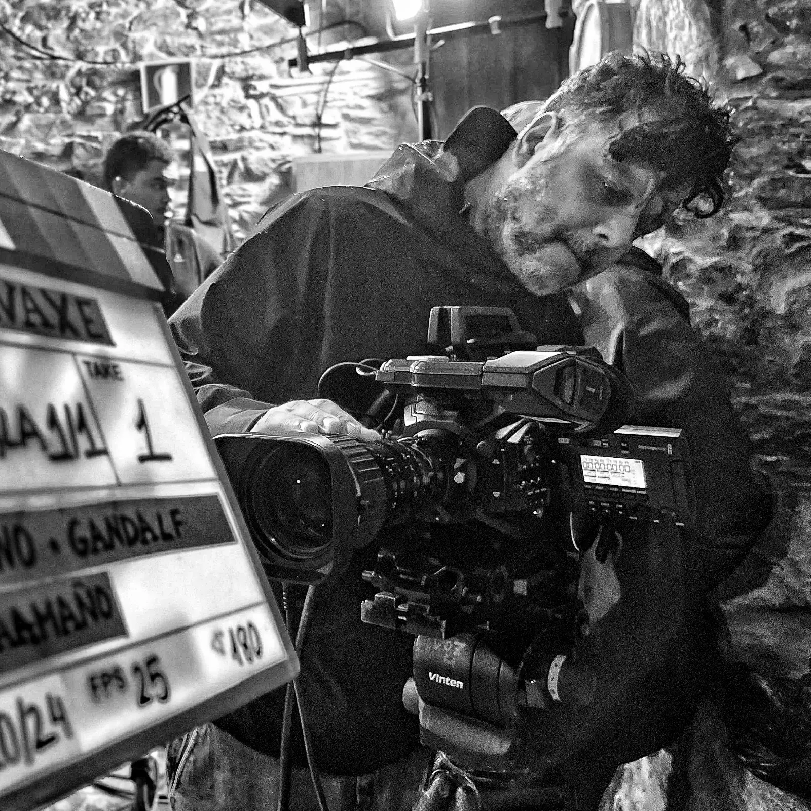 David Vilasboas con la cámara al hombro en el rodaje de VAXE, en blanco y negro.