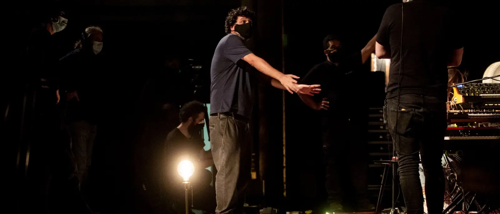 Ensayo sobre un escenario a oscuras, con el equipo marcando posiciones.